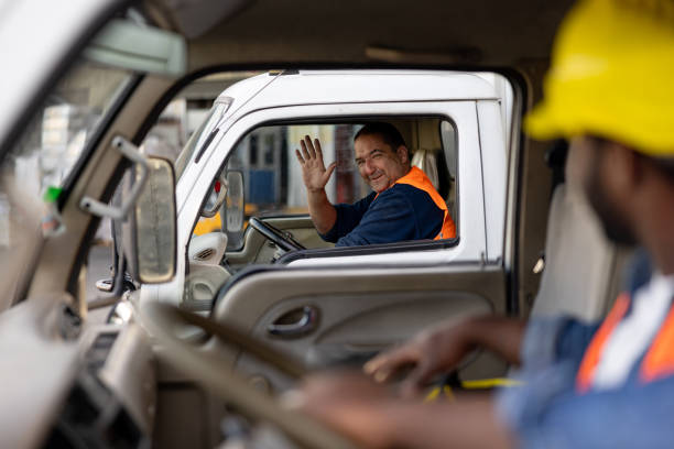image of a truck driver looking through his window and waving at another logistics driver