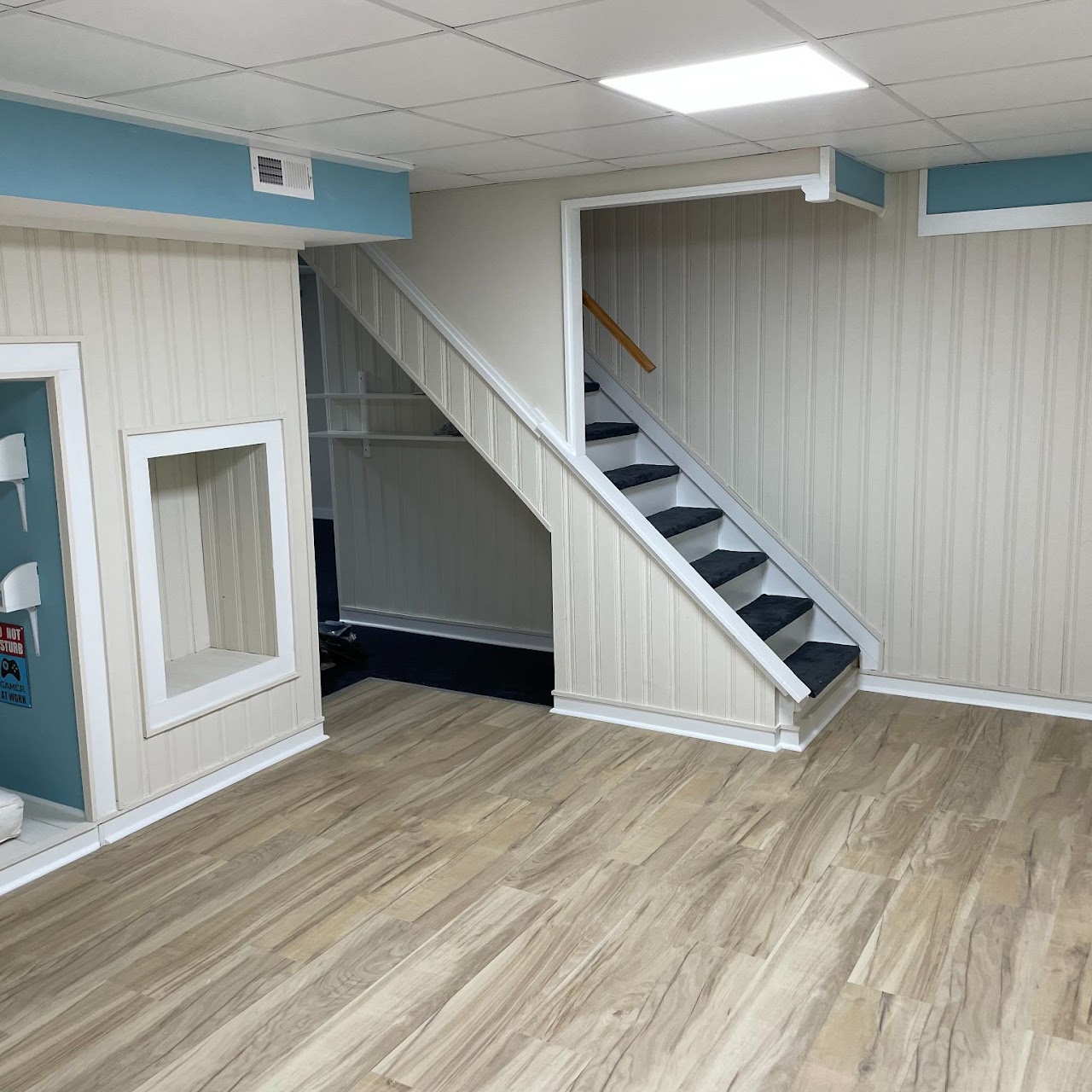 Remodeled basement with carpeted staircase and wood-look vinyl flooring
