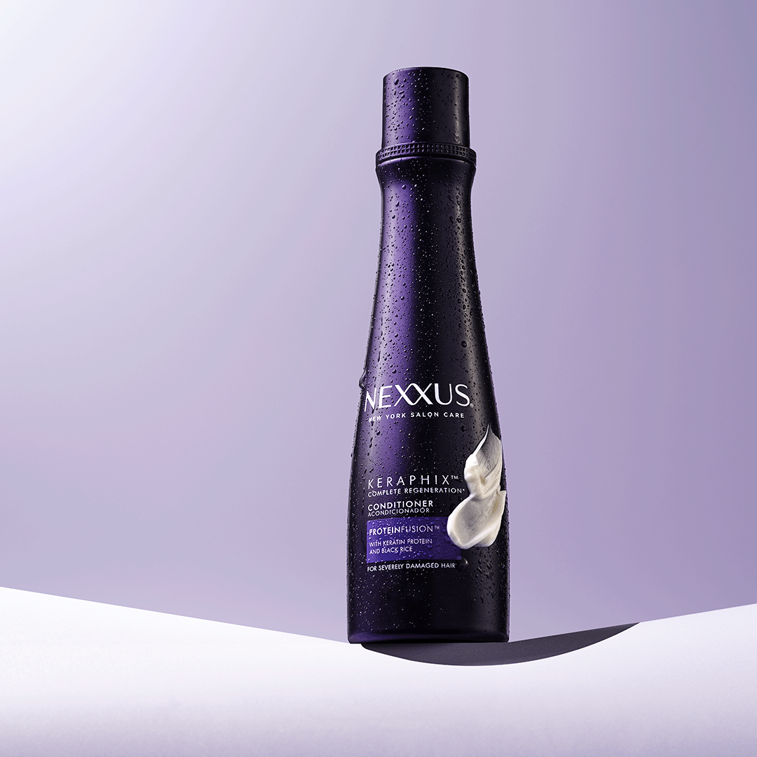 A sleek, dark purple bottle stands on a light surface with a subtle gradient background, showcasing its elegant design.