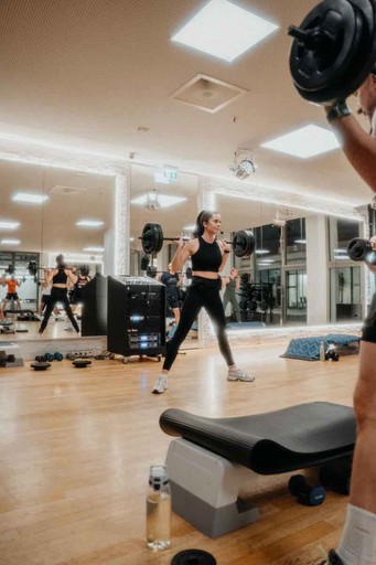 Kursleiterin mit Langhantel im Kursraum