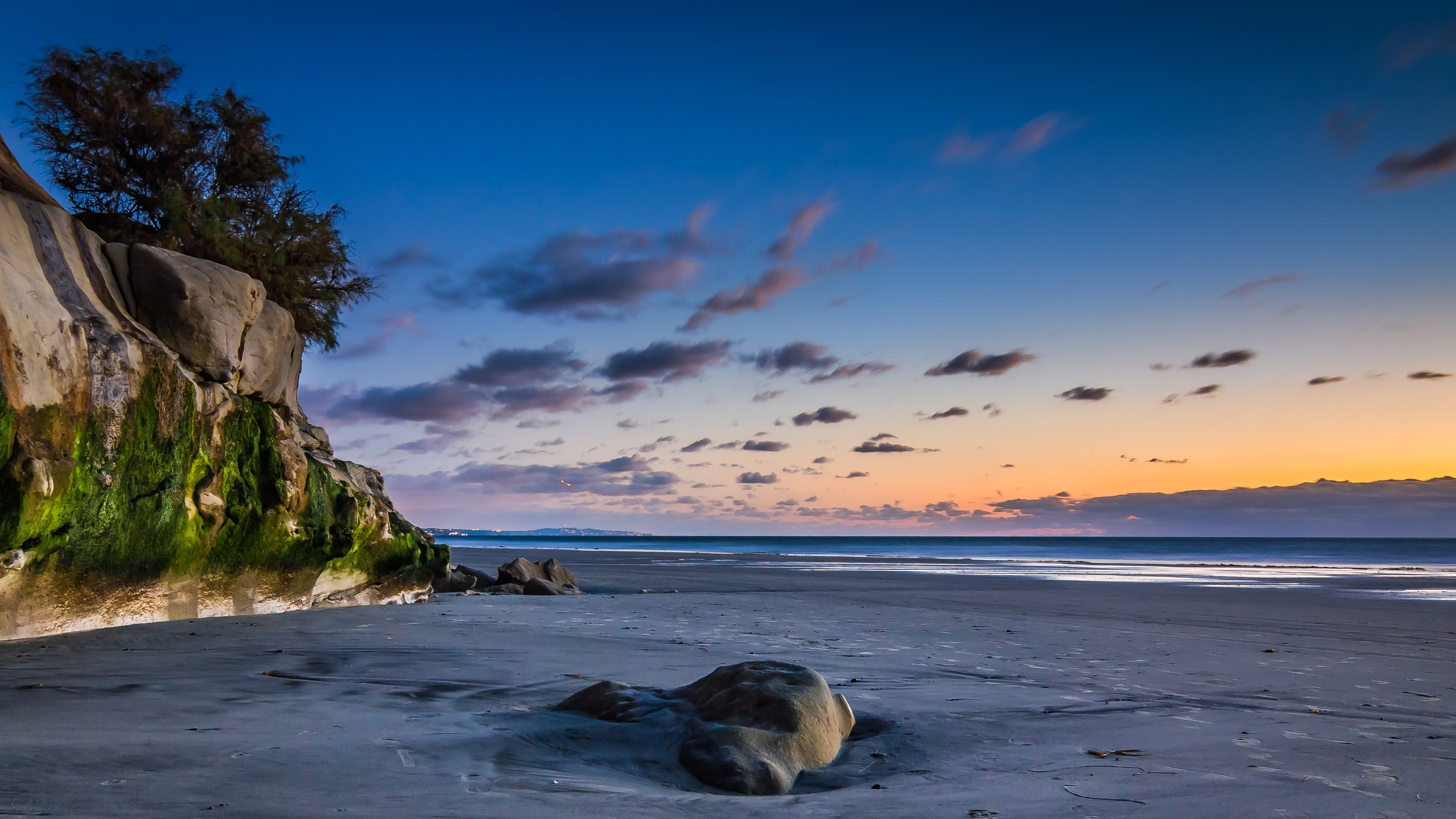 Modern indoor space with large glass doors, lush greenery, and a cozy seating area visible beyond.