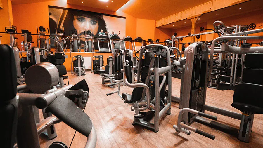 Large house with a wrap-around balcony overlooking a lit pool and deck at night.