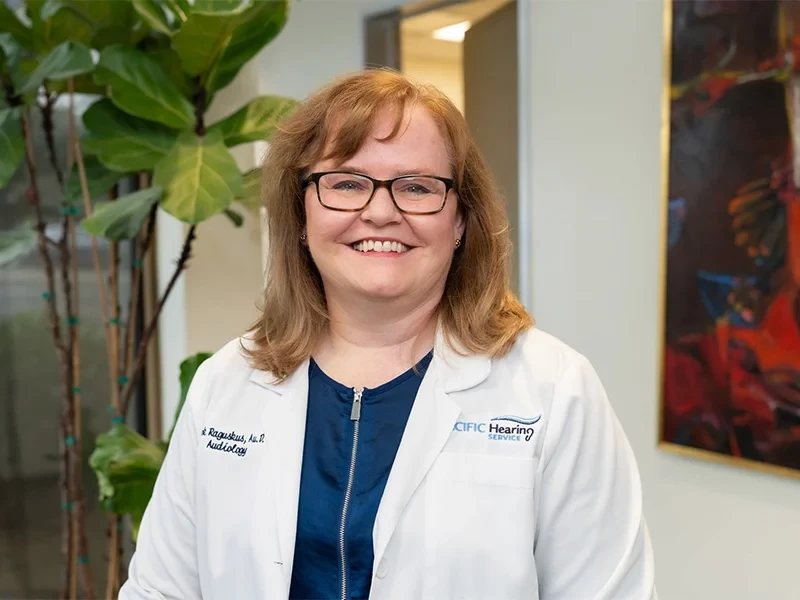 person writing on brown wooden table near white ceramic mug