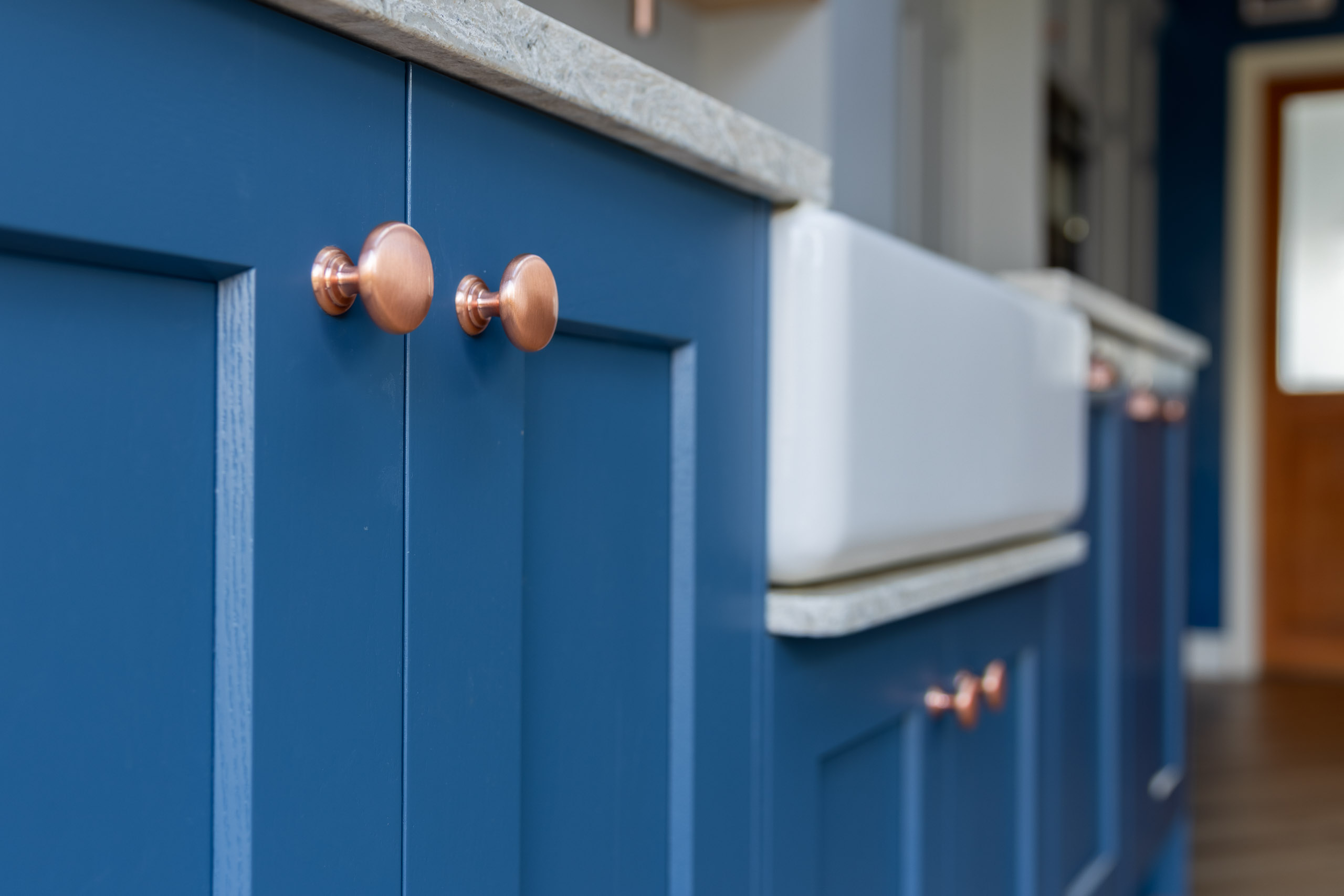 blue shaker kitchen with copper handles and belfast sink