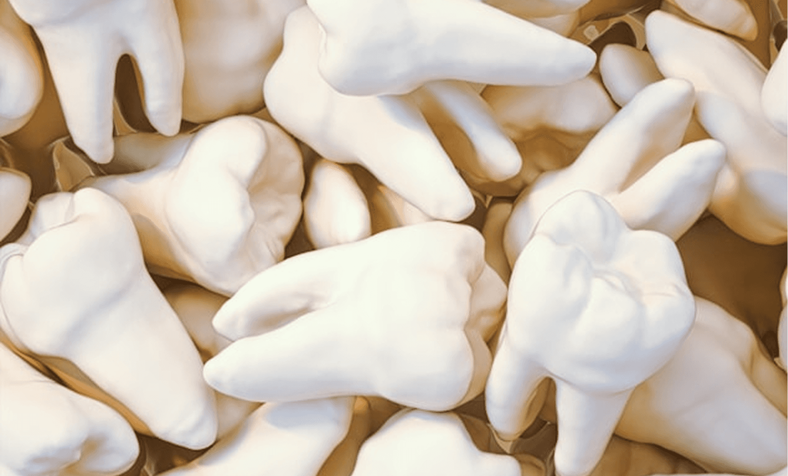 The image shows a collection of oversized, realistic-looking teeth models scattered in close proximity, highlighting dental health and oral hygiene themes.