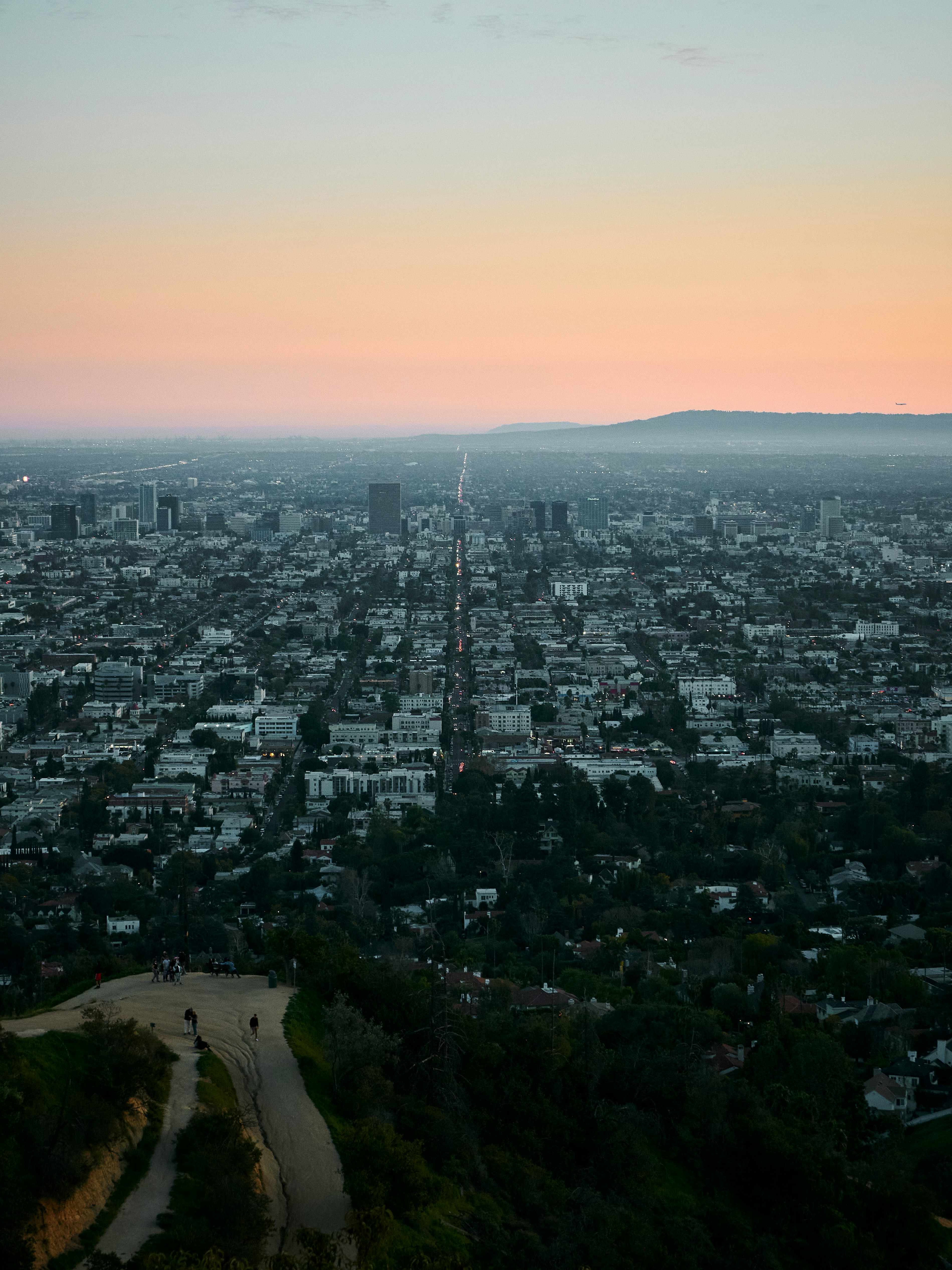 Aerial cityscape at sunset with freeways, neighborhoods, and commercial buildings