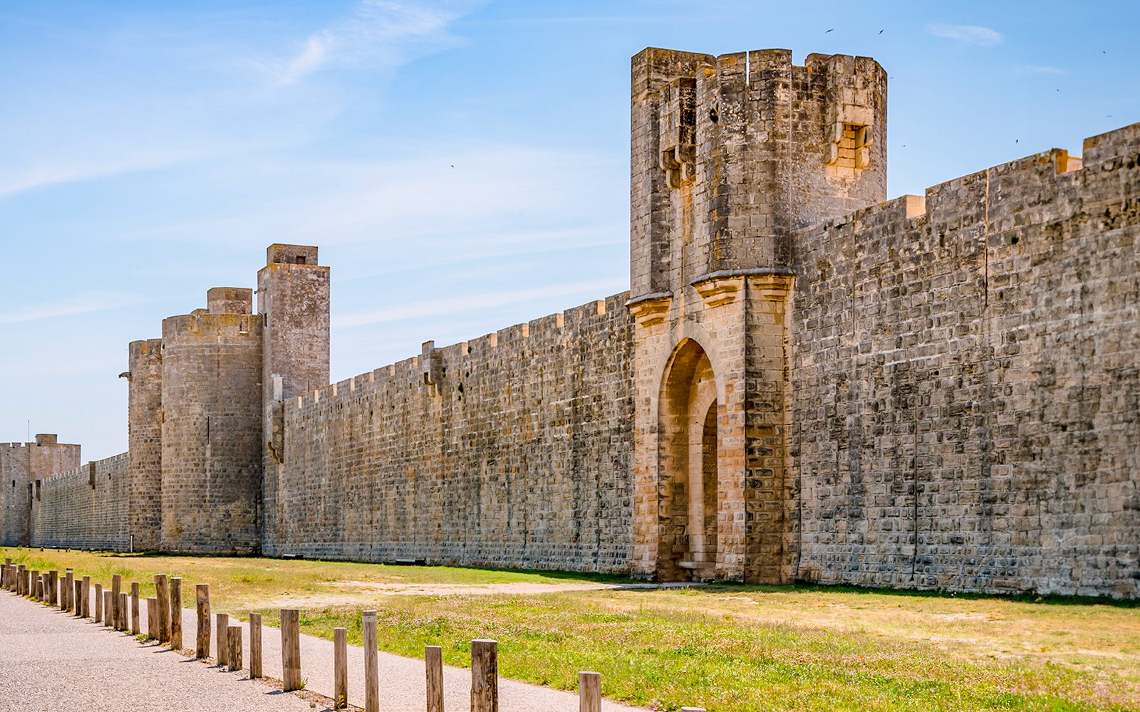 Towers and ramparts of Aigues-Mortes under a clear blue sky.