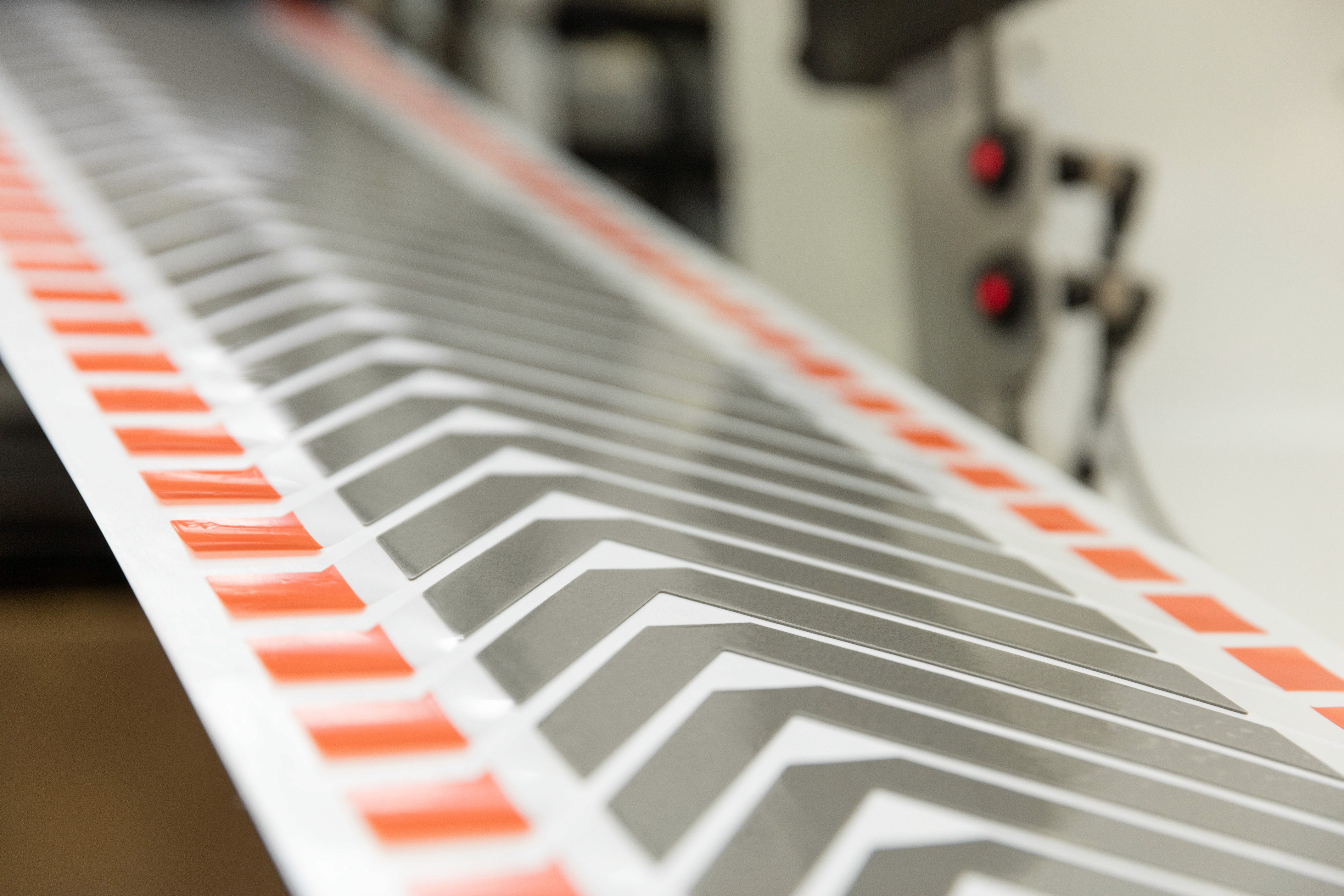 Nahaufnahme einer metallischen Oberfläche mit einem gemusterten Design mit orangefarbenen und weißen Markierungen.