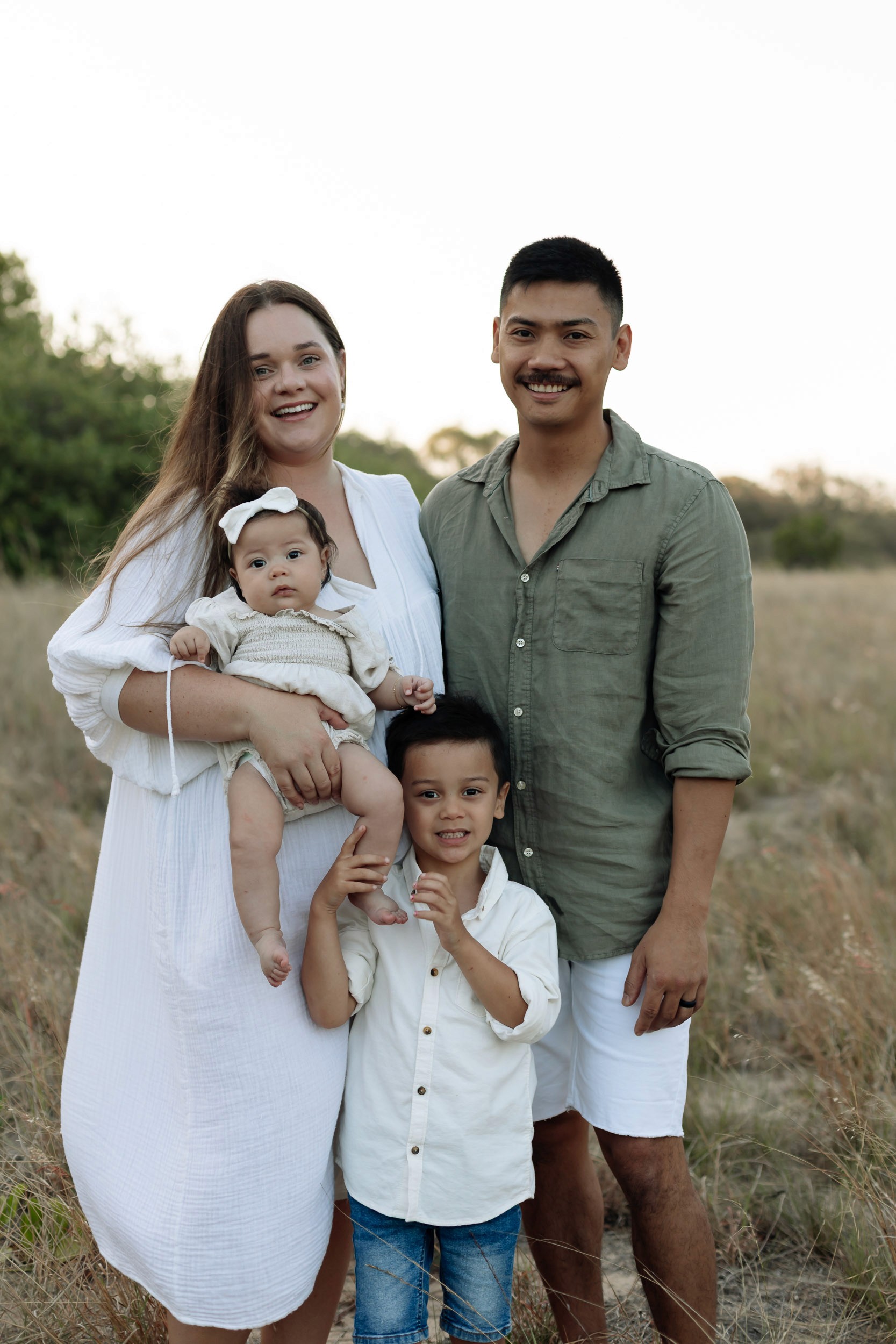 Outdoor family portraits in Mackay featuring a baby girl and young boy playing together in golden sunset light