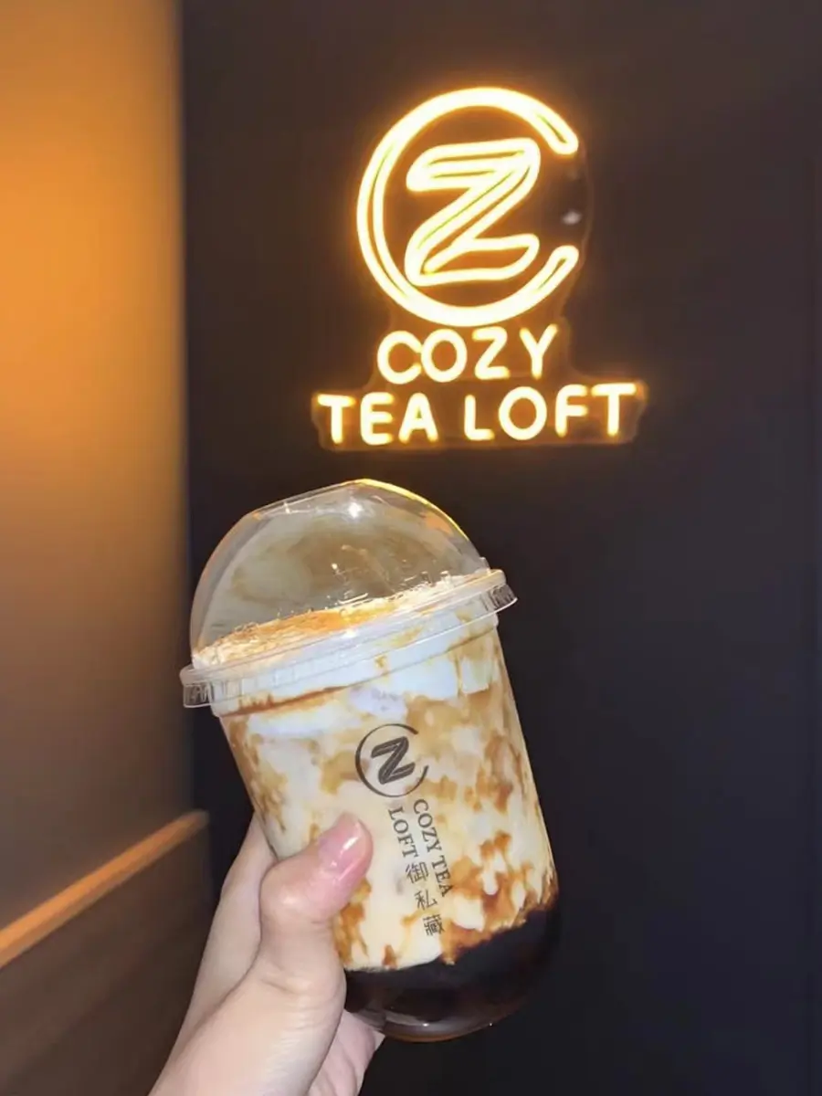 A stunning brown sugar boba drink from Cozy Tea Loft, featuring rich caramelized brown sugar streaks, creamy milk, and perfectly chewy tapioca pearls, capturing the essence of indulgent bubble tea.