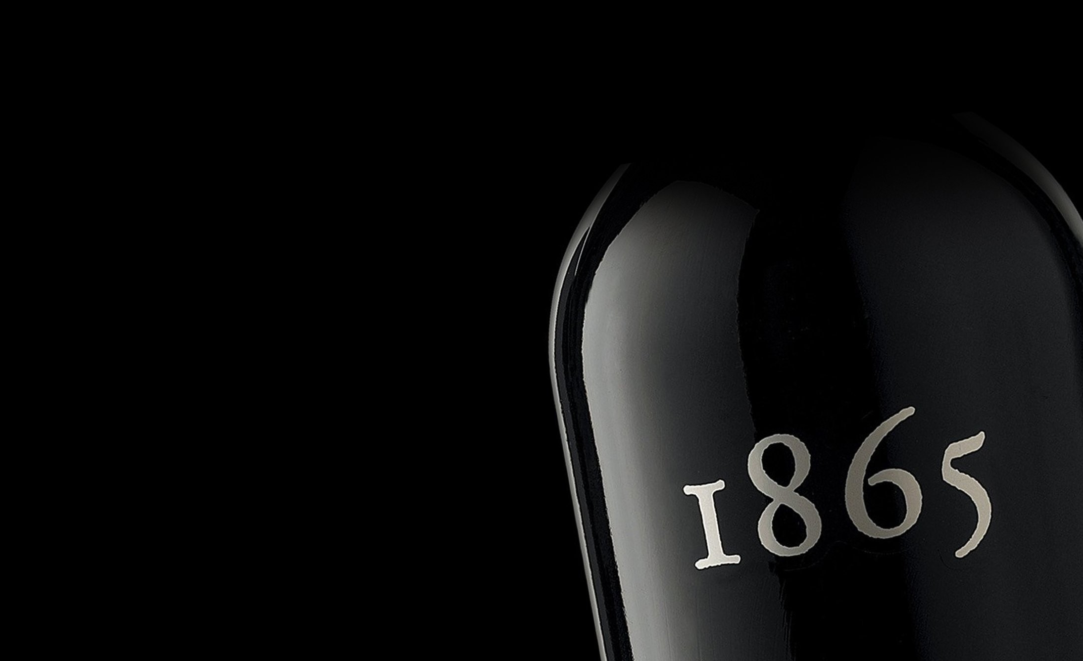 Close-up of a black wine bottle against a dark background. The bottle displays the number "1865" in elegant white font, suggesting a vintage feel.