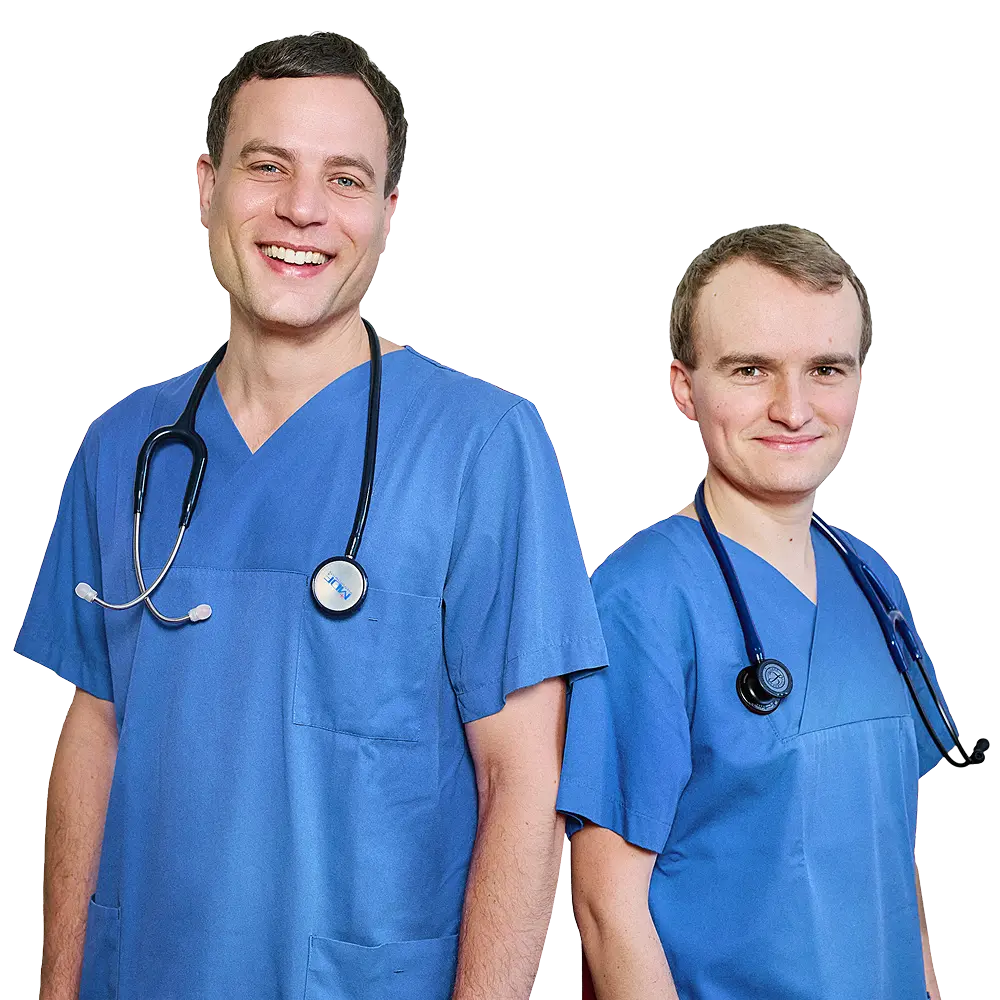 Dr. med. Juri Mattern und Dr. med. Marc Beier, zwei lächelnde Mediziner in blauen Kitteln, stehen selbstbewusst mit Stethoskopen um den Hals da.