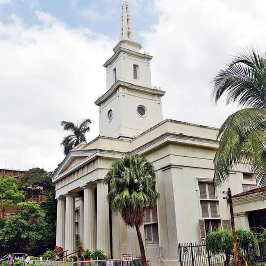 Outdoor restaurant terrace overlooking a tranquil lake at sunset. White tables and chairs are set with glassware. Sheer curtains add elegance. Calm ambiance.