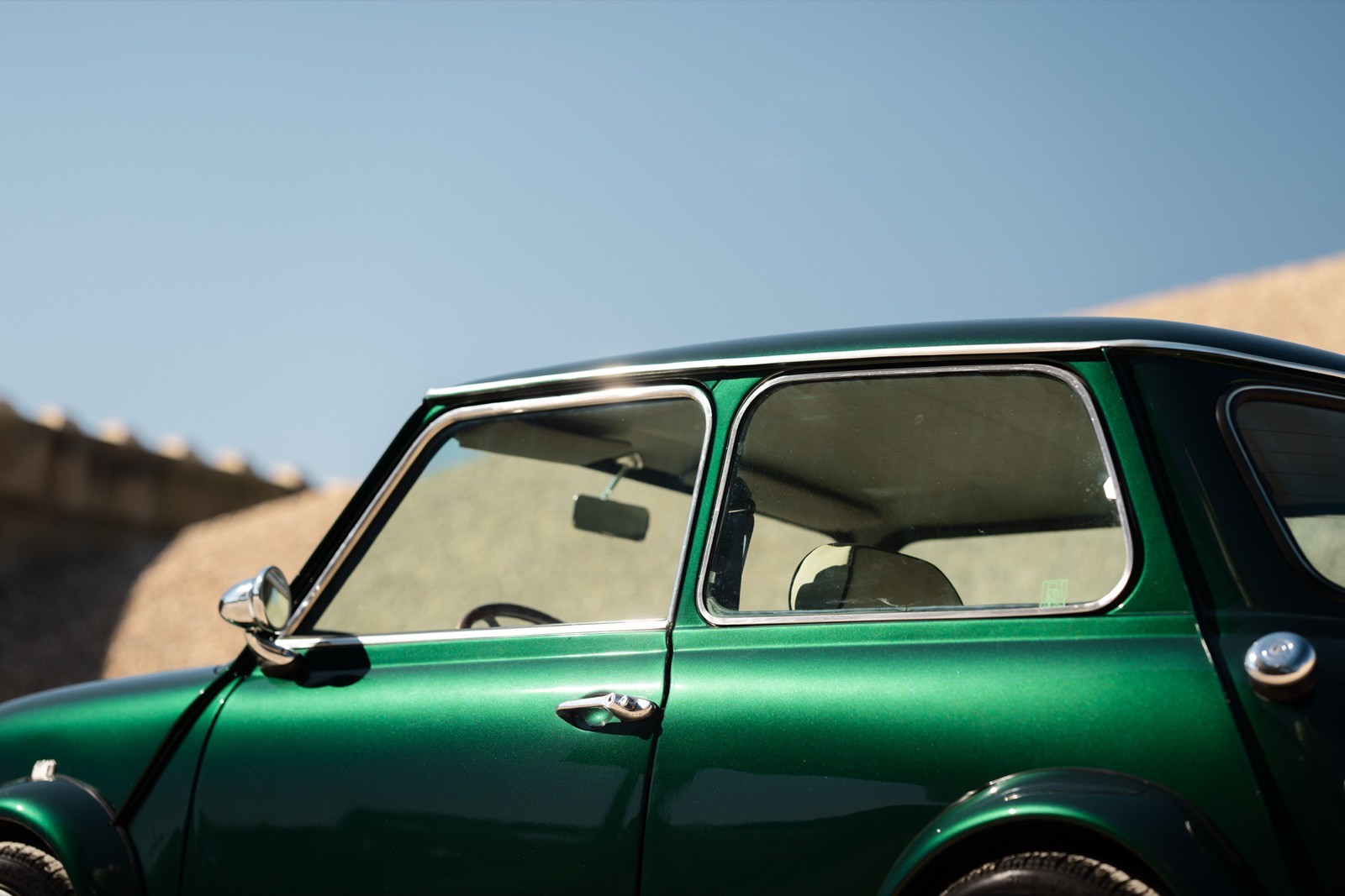 A small, green and black vehicle parked on a sandy surface, with a warm sunset lighting the scene.
