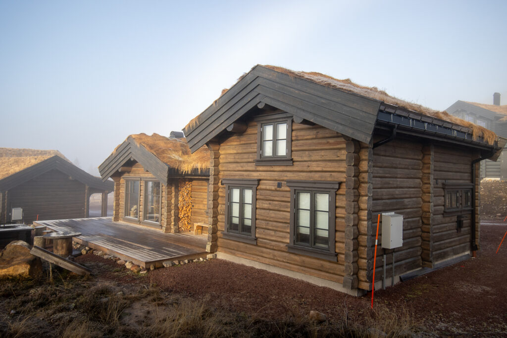 Side angle of log cabin exterior in misty weather with soft lighting.
