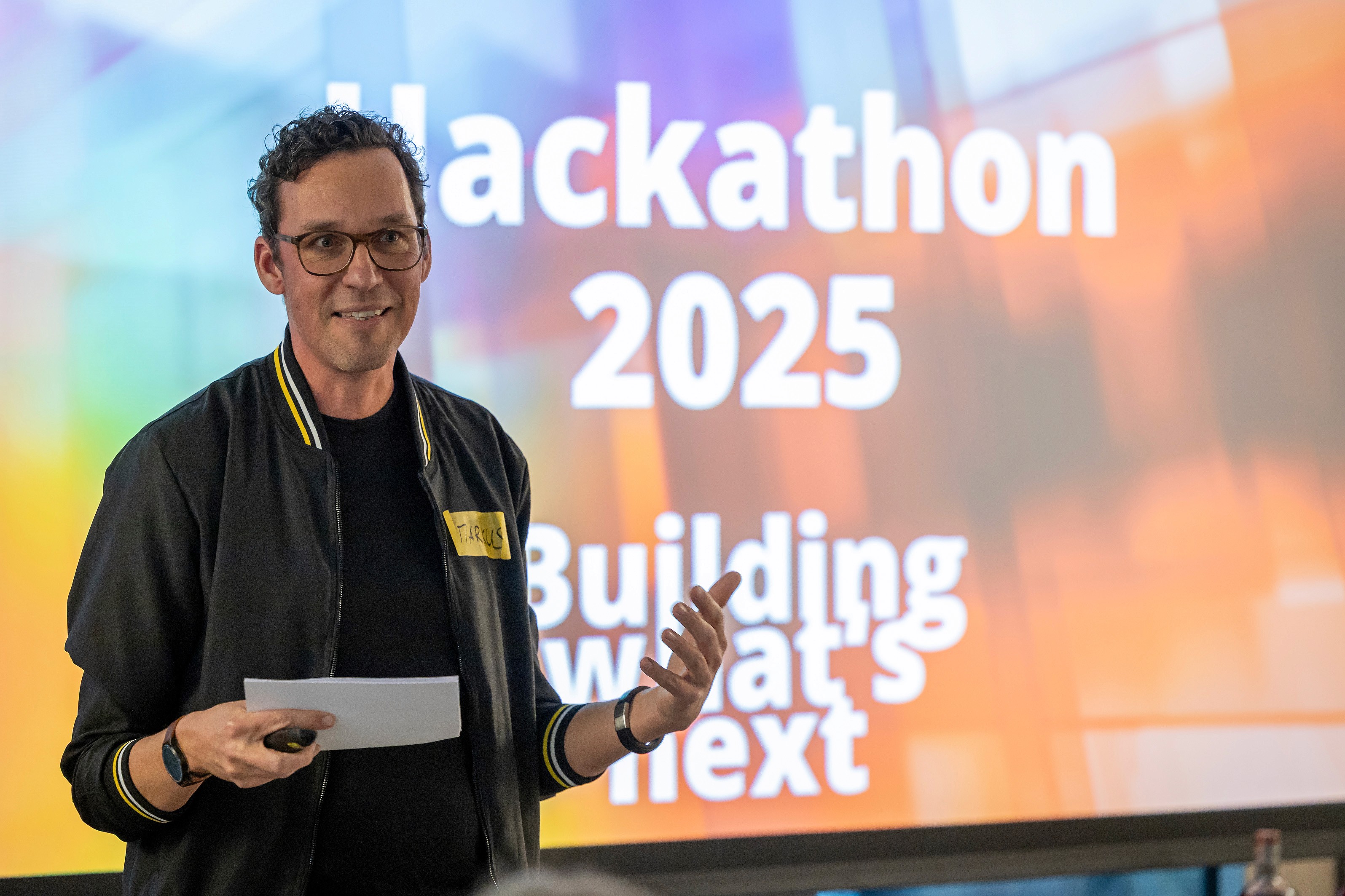 People crossing a busy street with cars and buildings.