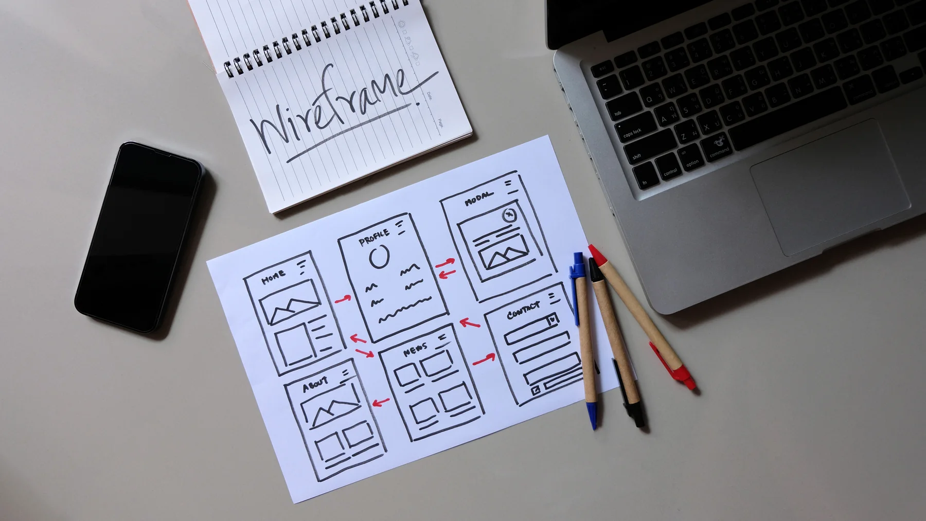 Laptop and Phone Next to Wireframe Drawings