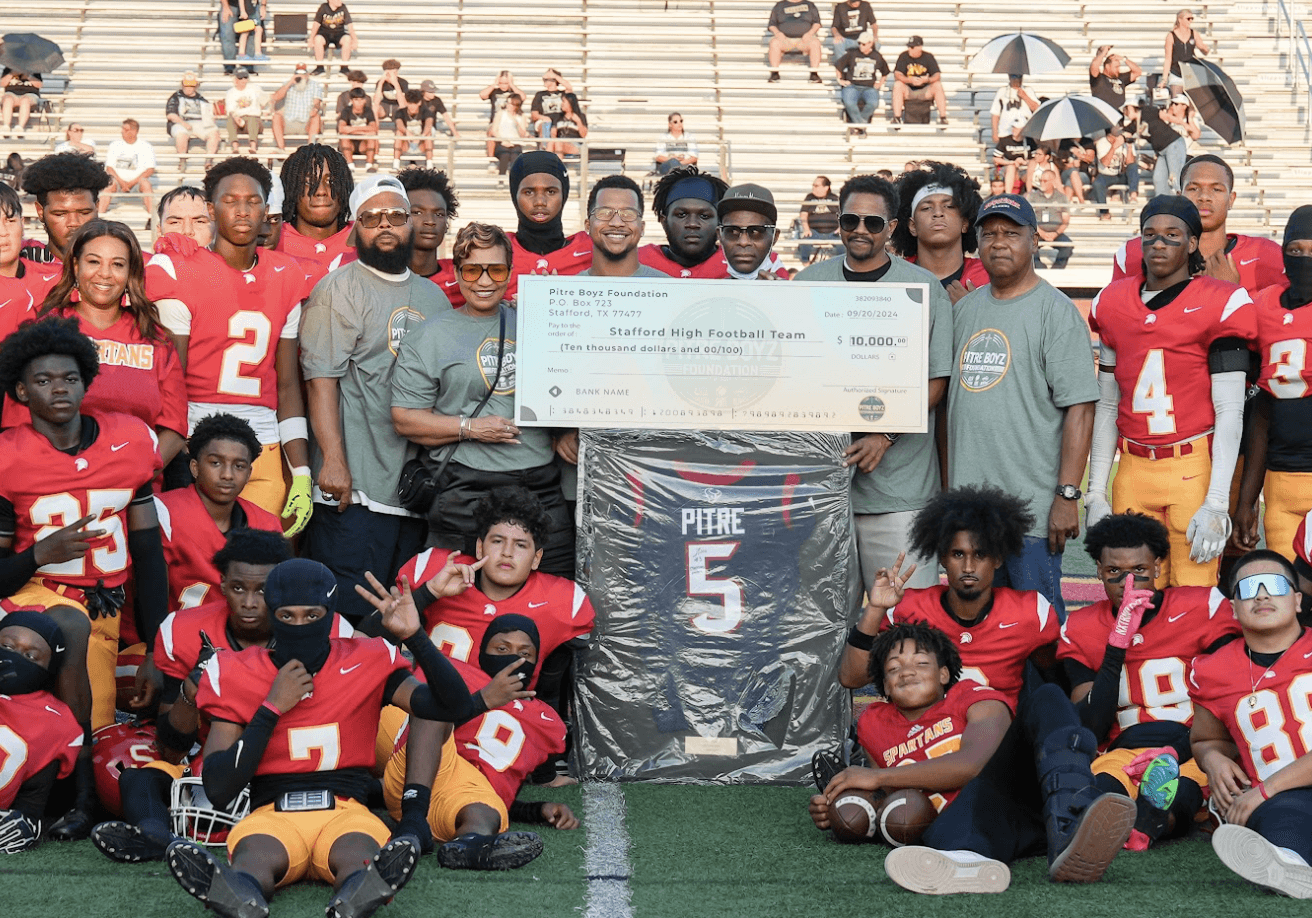 Foundation members holding a donation check with a football team.