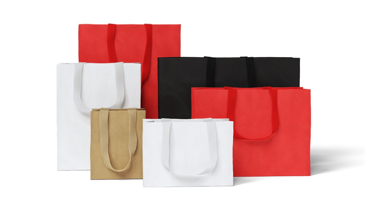 Red, black, white and kraft paper shopping bags with ribbon handles on a white background