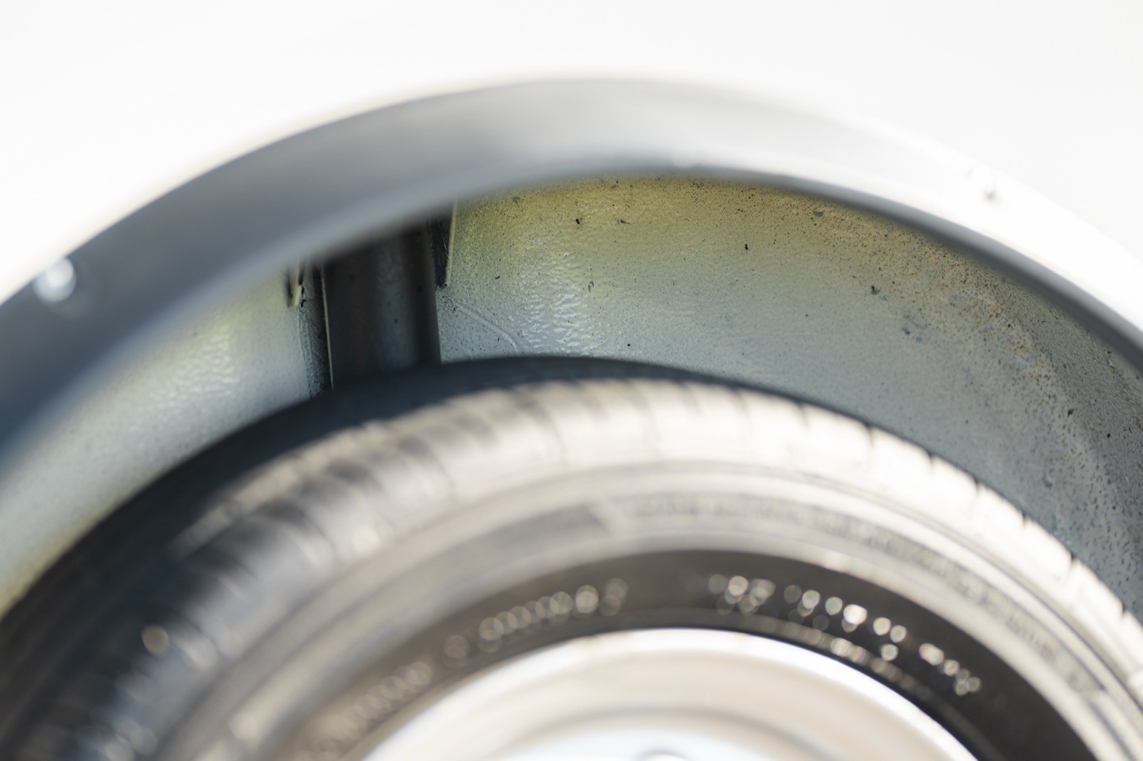 Close-up of a vehicle's wheel area, showing tire tread and part of the wheel rim.