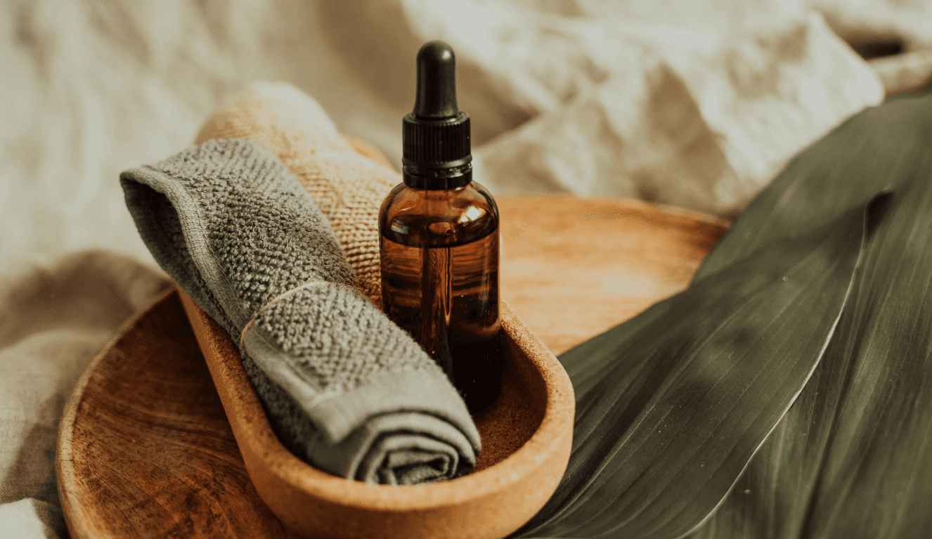 A spa side table with face towel, serum, and palm leaves.