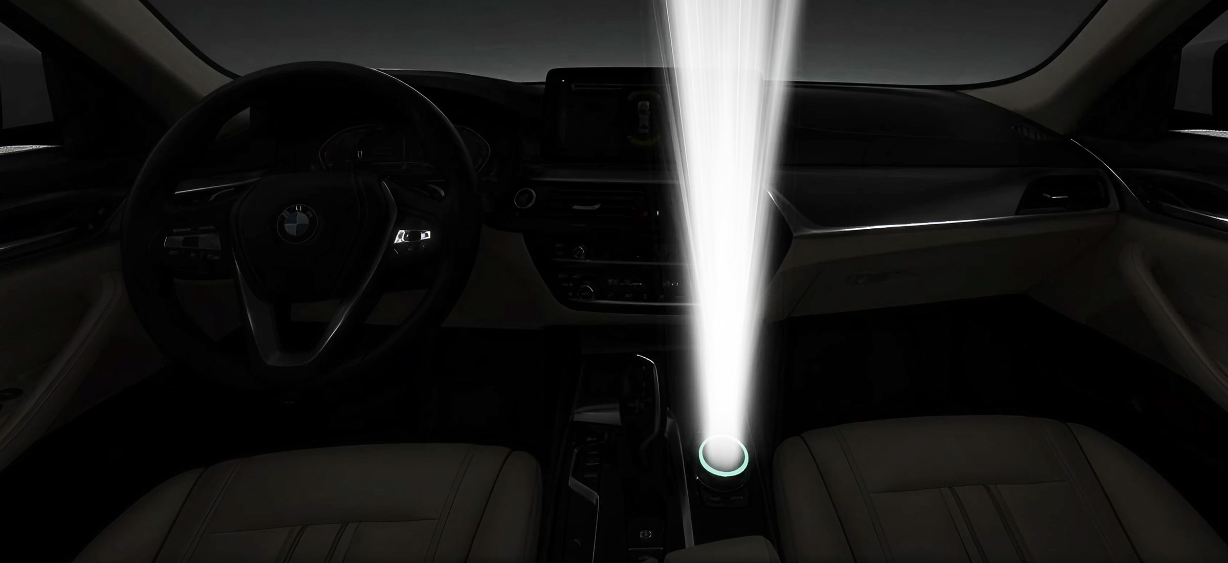 BMW interior at night with a bright white light beam projected upward from the centre console