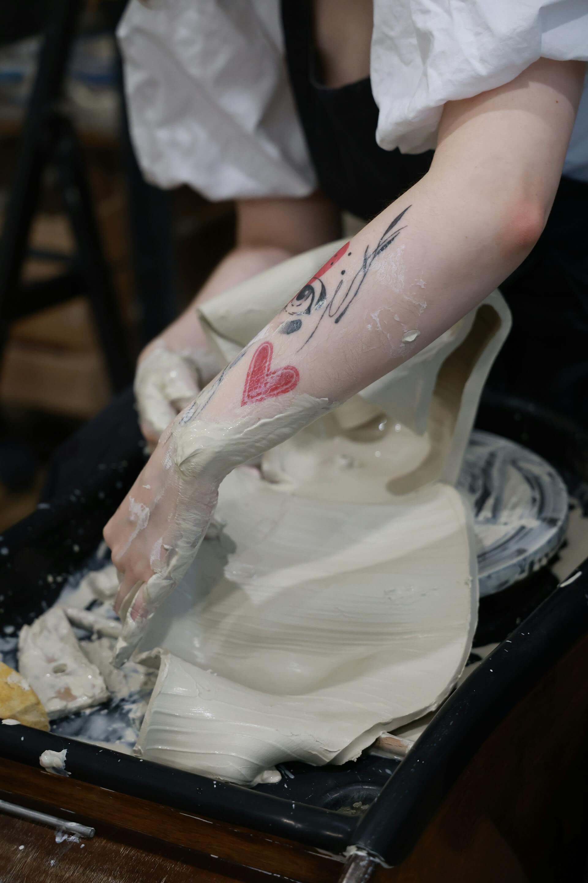 A woman shapes a pottery piece, delicately crafting a heart design on its surface