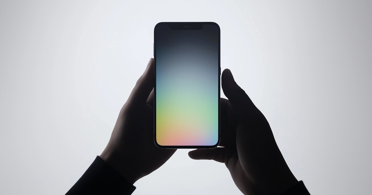Person holding a smartphone with a colorful gradient screen in front of a light background.
