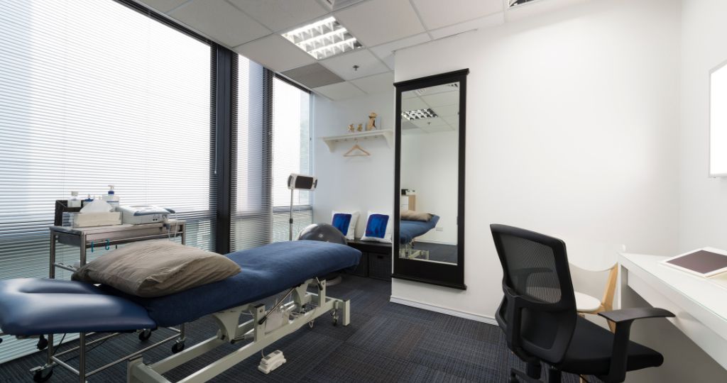 Chiropractic clinic with a treatment table, office desk, and medical equipment