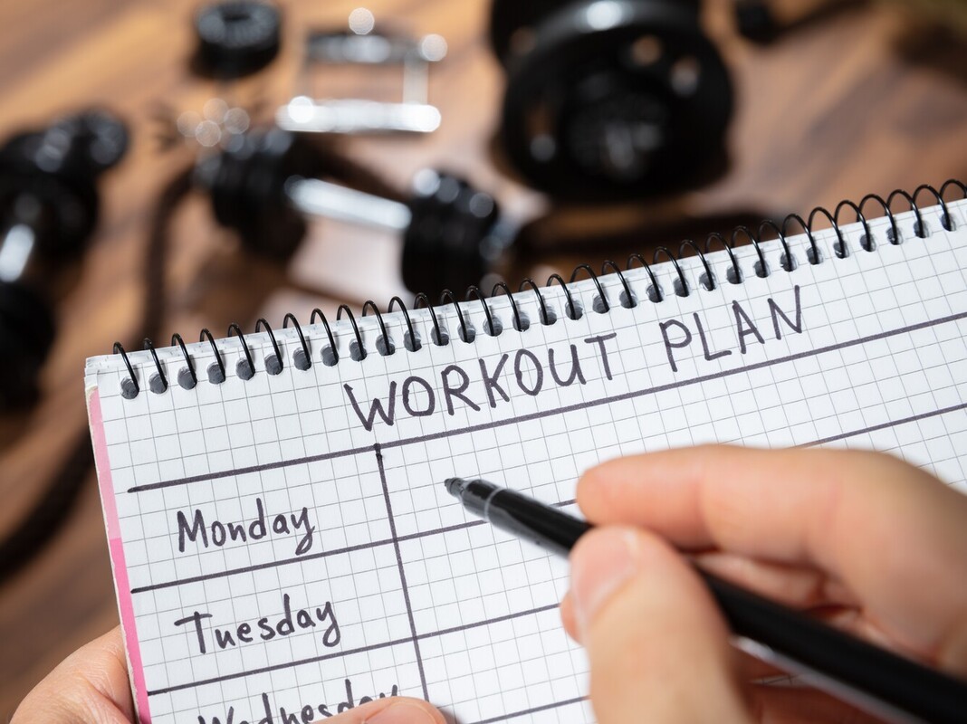 closeup of a person writing their weekly plan for good at home workouts to lose weight in a notebook