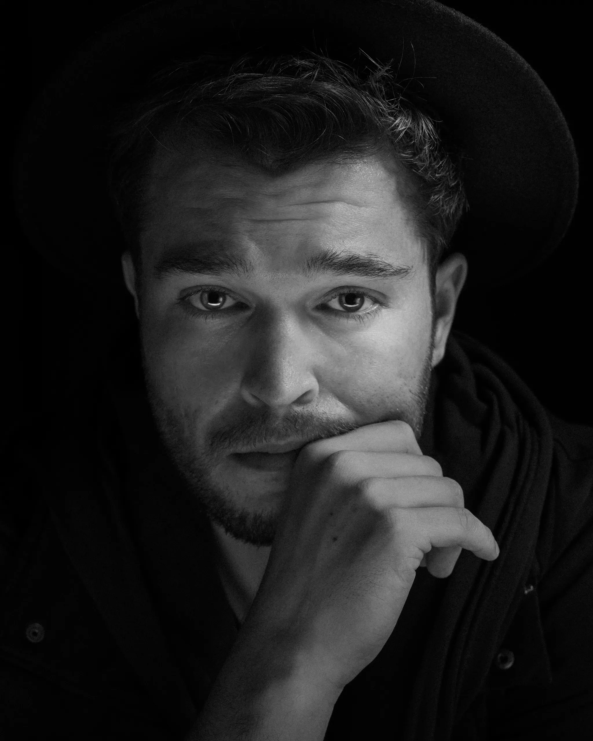 Black and white portrait of the artist Zian wearing a hat and looking thoughtful.