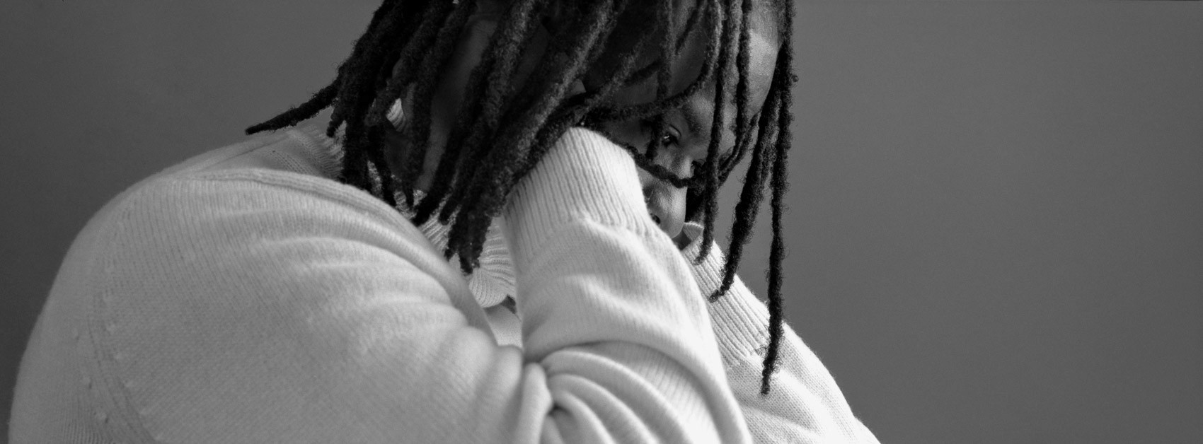 Film photography with flash: Model sitting with his arms behind his back, partly obscuring his face  using Hasselblad XPan,Shot with the Godox AD600, close-up panoramic portrait of model in thought, black and white Ilford Delta.