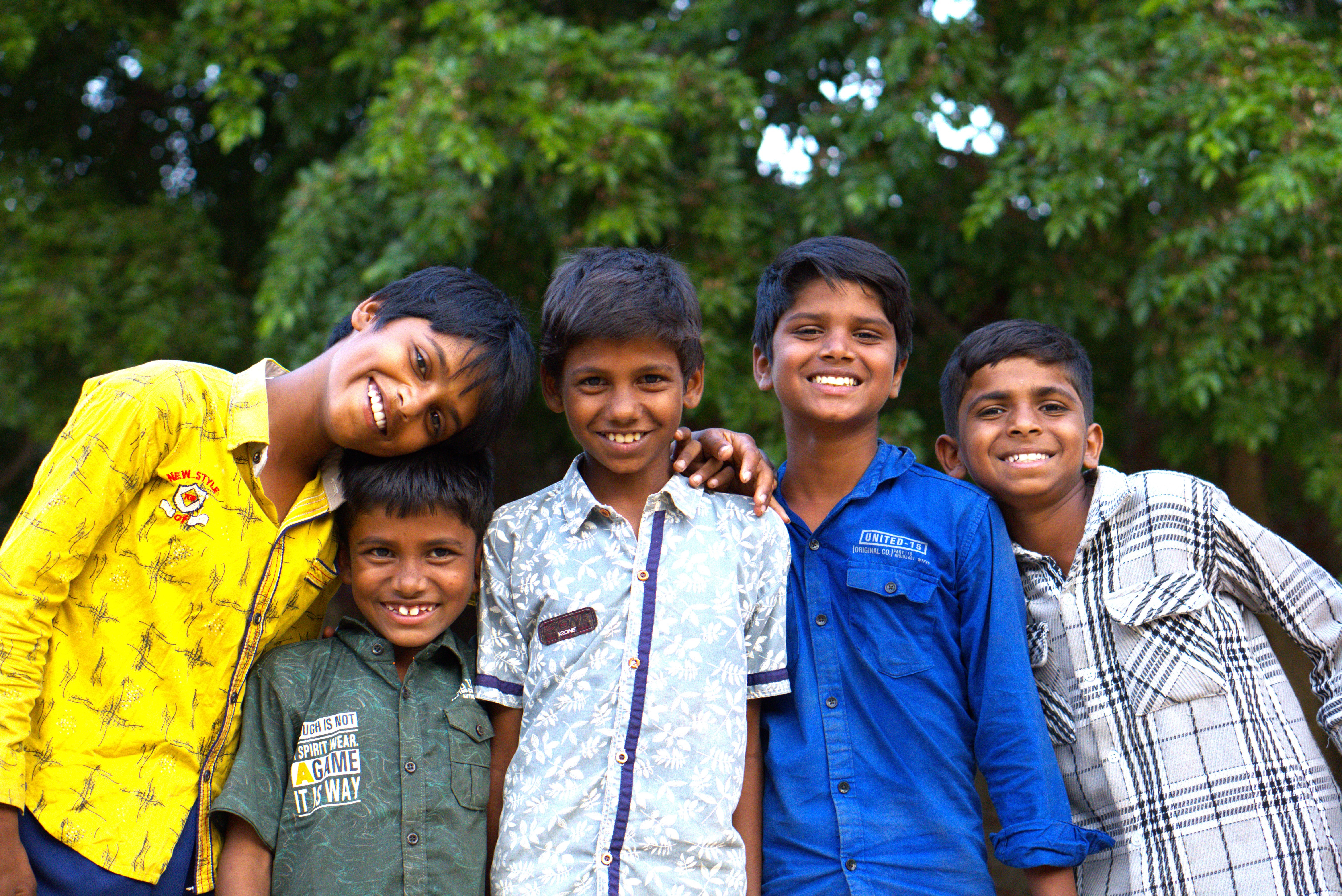 five children smiling while doing peace hand sign