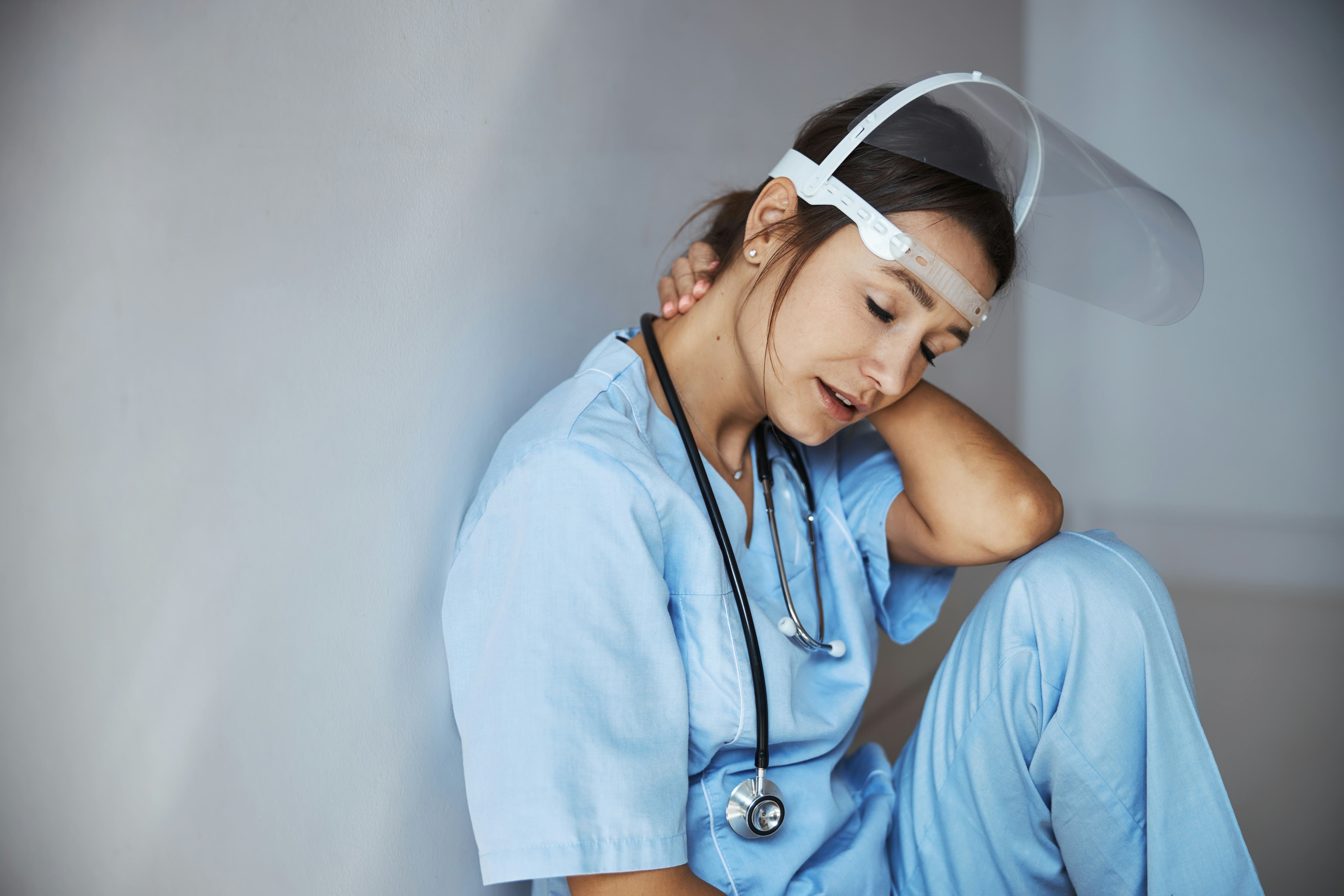 a stressed veterinarian slumped against the wall and holding her neck