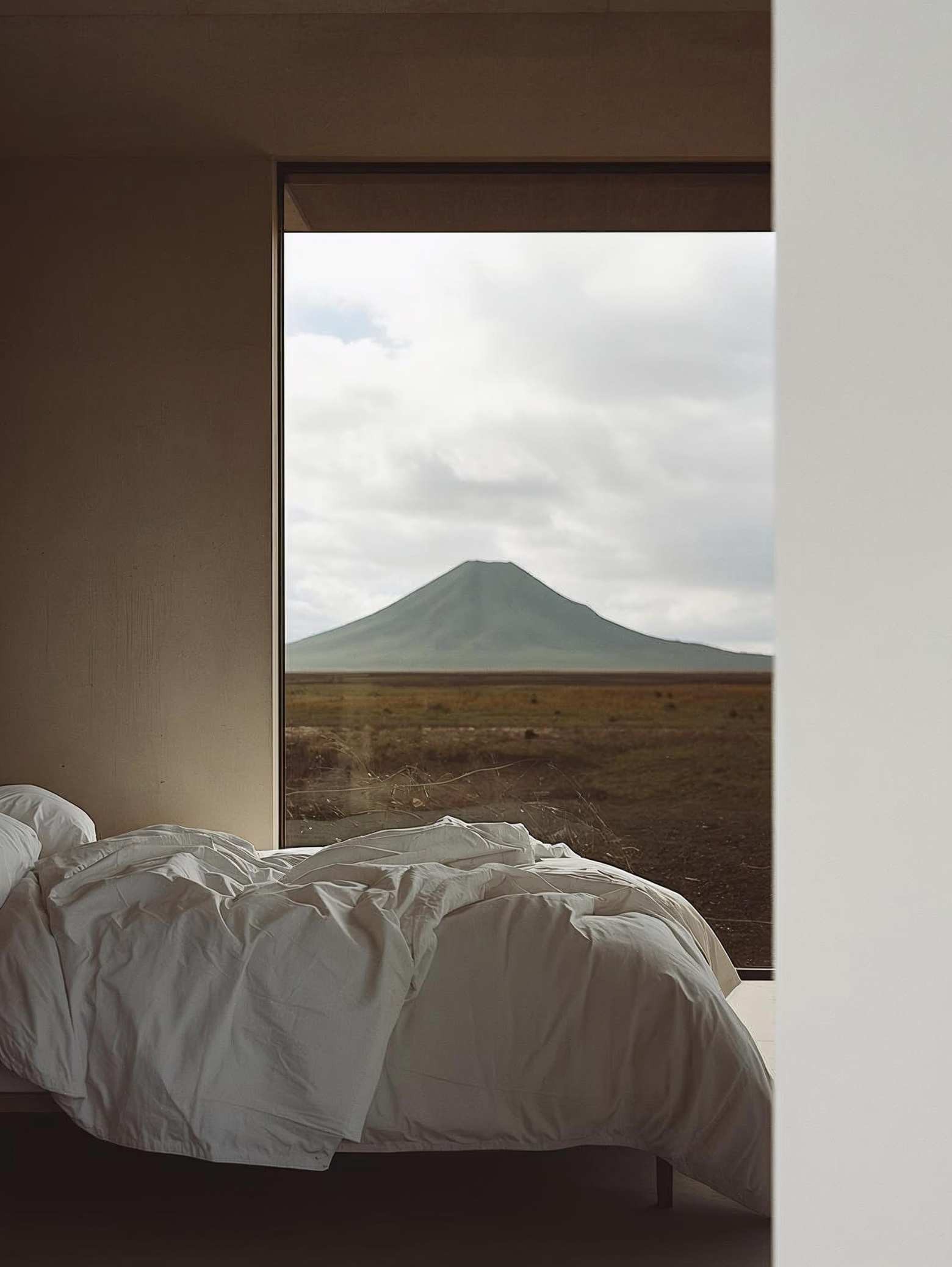 Minimalist hotel room with open window overlooking a mountain landscape, showcasing organic travel and hospitality visual storytelling by Casa Clara Studios.