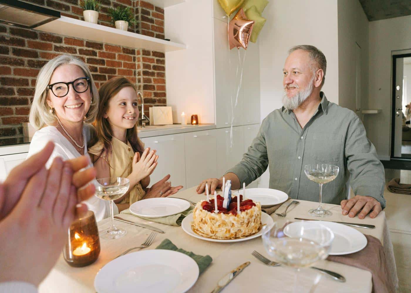 Man, woman and younger girl sitting at dinner table with a birthday cake in front of them