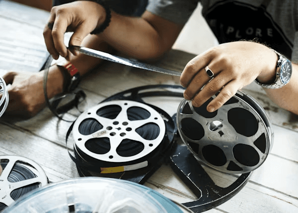 High school student conducting film studies research with a PhD mentor reviewing a screenplay analysis and academic journal