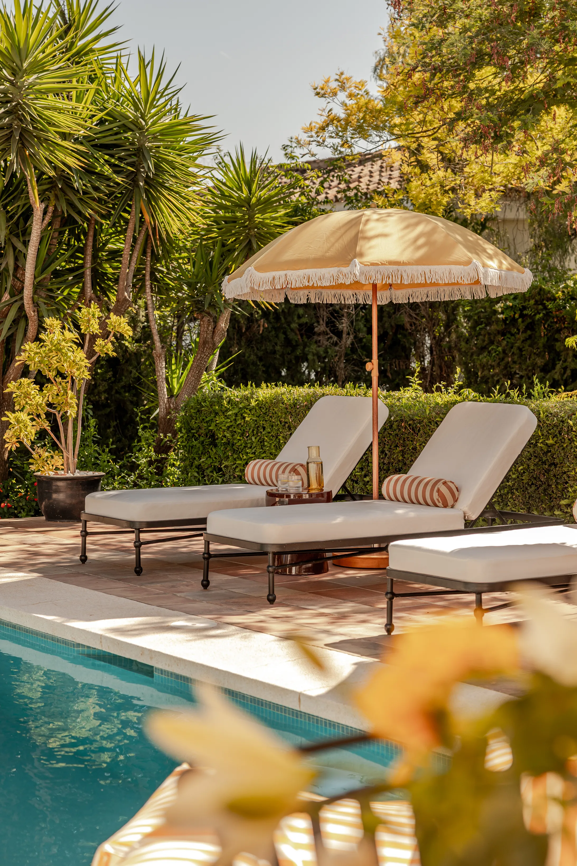 Luxury poolside terrace with sun loungers surrounded by lush Mediterranean landscaping.