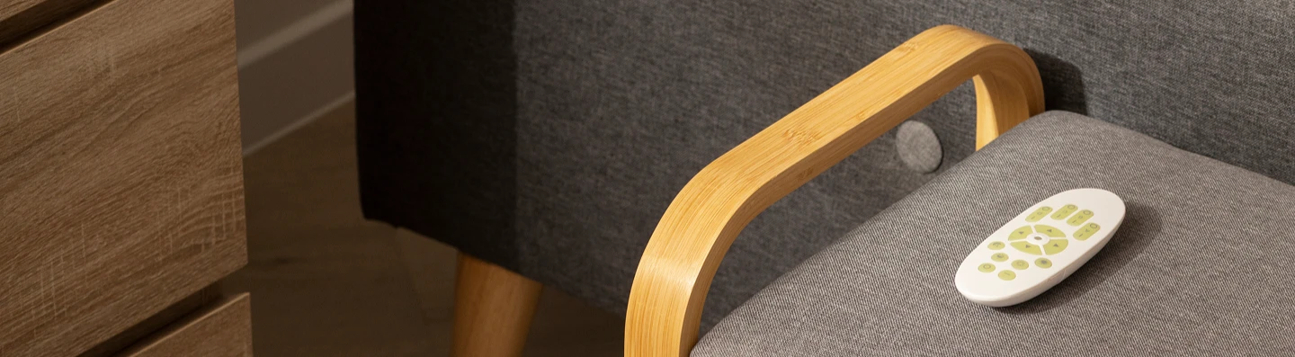 Cozy bedroom corner with a wooden bench, gray cushion, and slippers underneath.