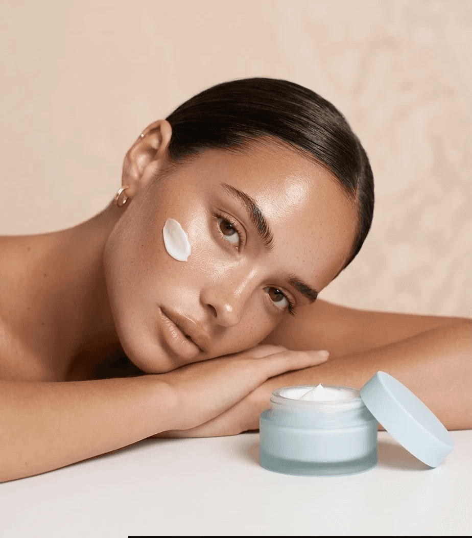 Model with face cream swatch next to open moisturizer jar