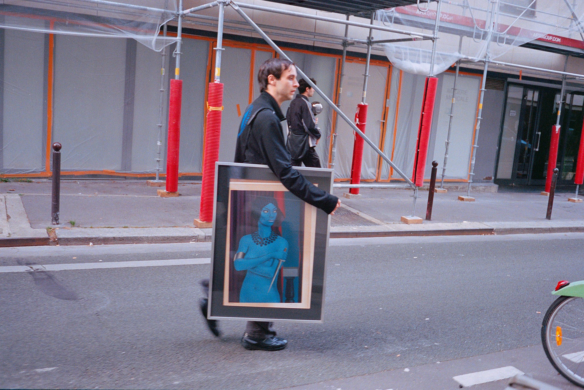 Un homme en noir portant un tableau dans la rue