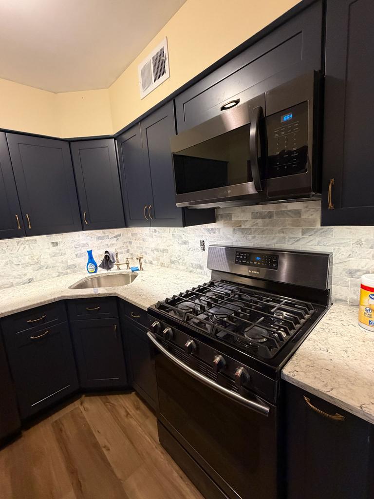 Dark shaker kitchen with granite countertops and a gas range