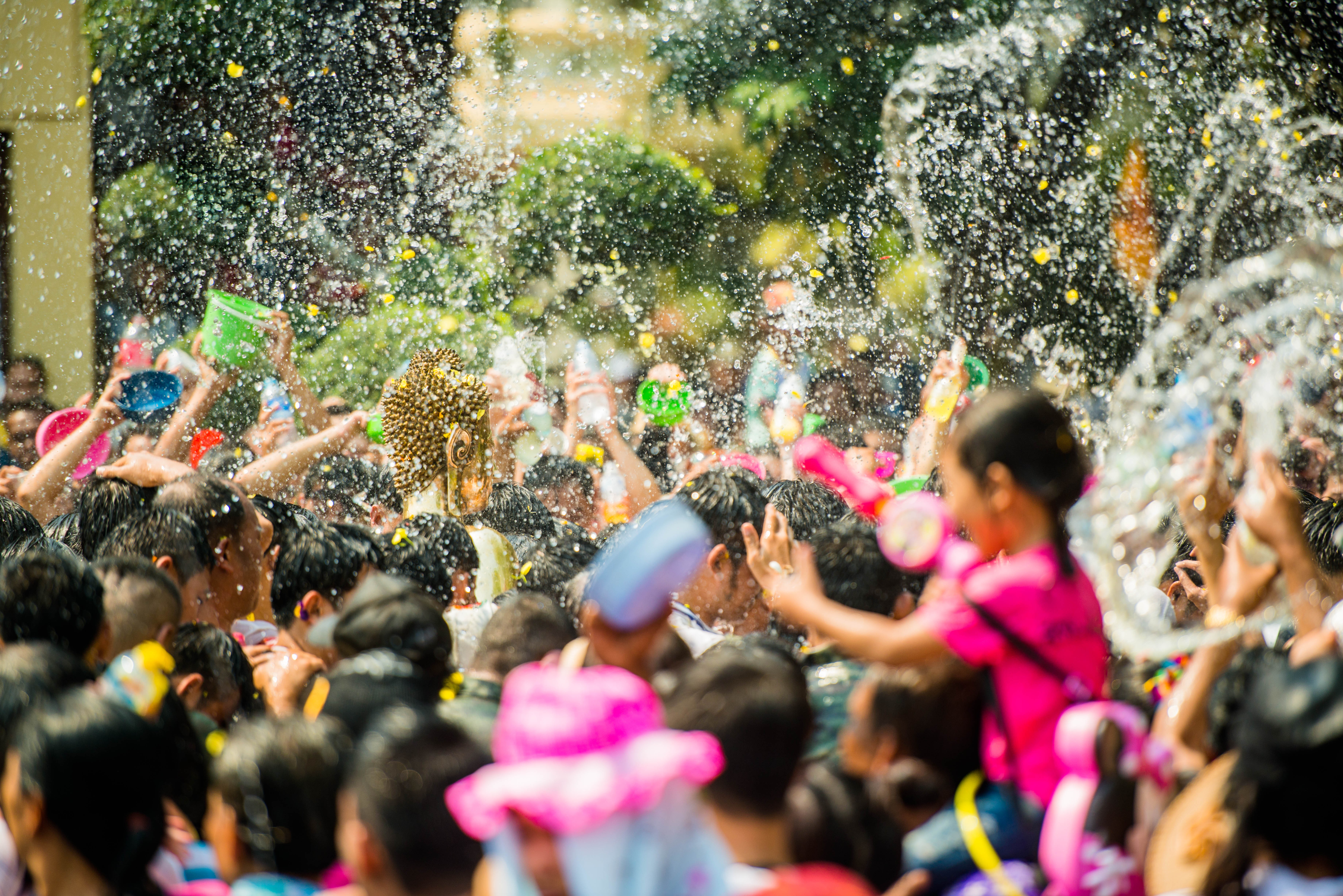 A happy crowd of people throwing buckets of water at each other as part of Thailand's Songkran festival