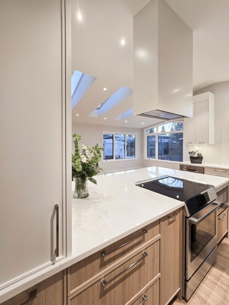 Image of Modern kitchen design with large island, skylights, and stainless steel appliances by KHD Homes.