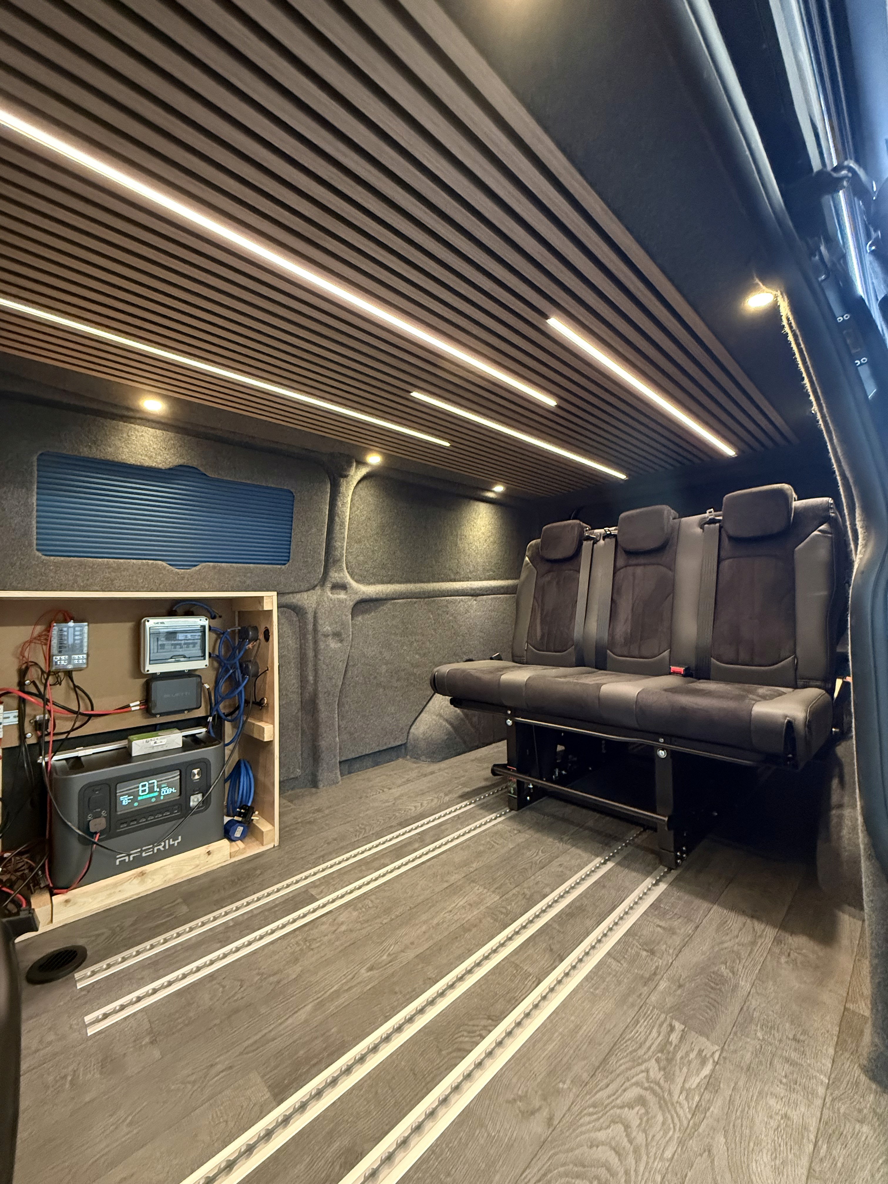 Carpet-lined campervan interior with seating and wooden furniture