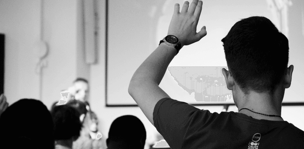 A young man in an audience raising his hand.