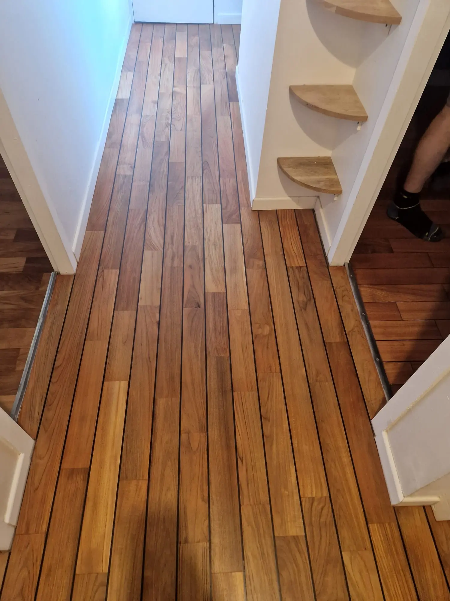 Parquet pont de bateau posé dans un couloir avec joints noirs