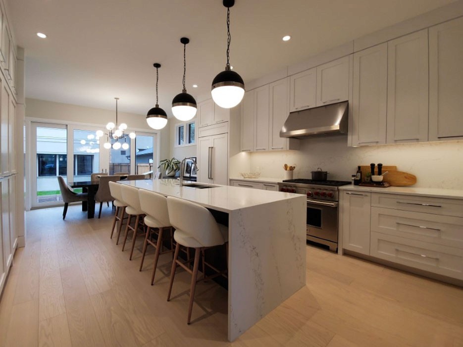 Image of Modern kitchen design with marble island, pendant lights, and white cabinetry by KHD Homes.