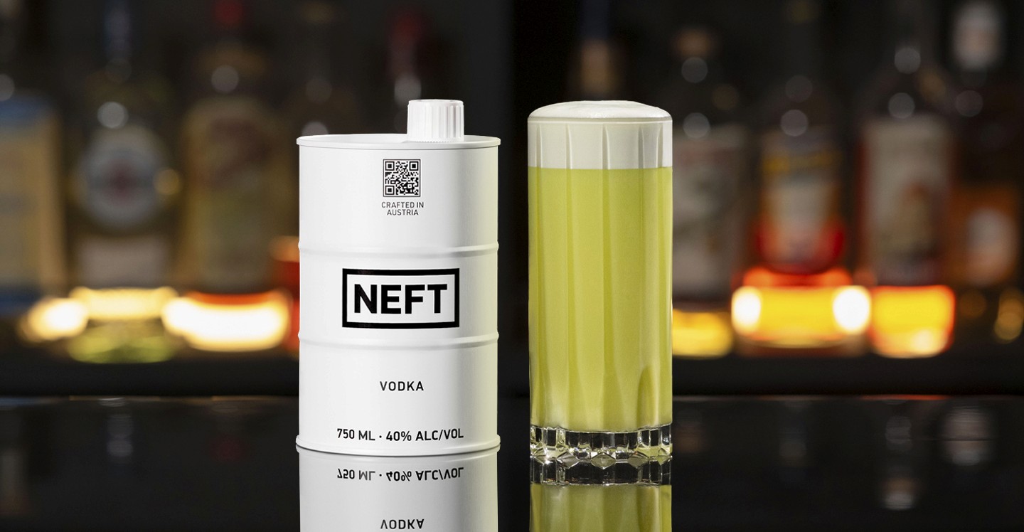 A NEFT Barrel and a glass of P.E. & J. on a bar counter.