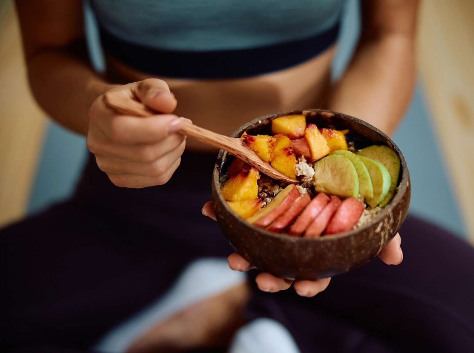 oman sitting on her yoga mat eating a healthy meal after doing the best yoga for weight loss